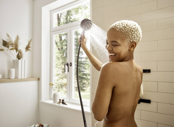 Woman showering under the linear Raindance Alive overhead shower.