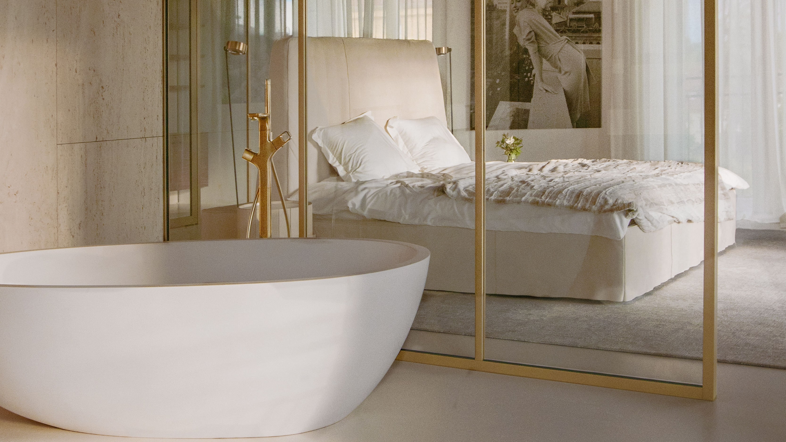 Luxusní koupelna en suite, oddělená skleněnými stěnami s mosazným lemováním.