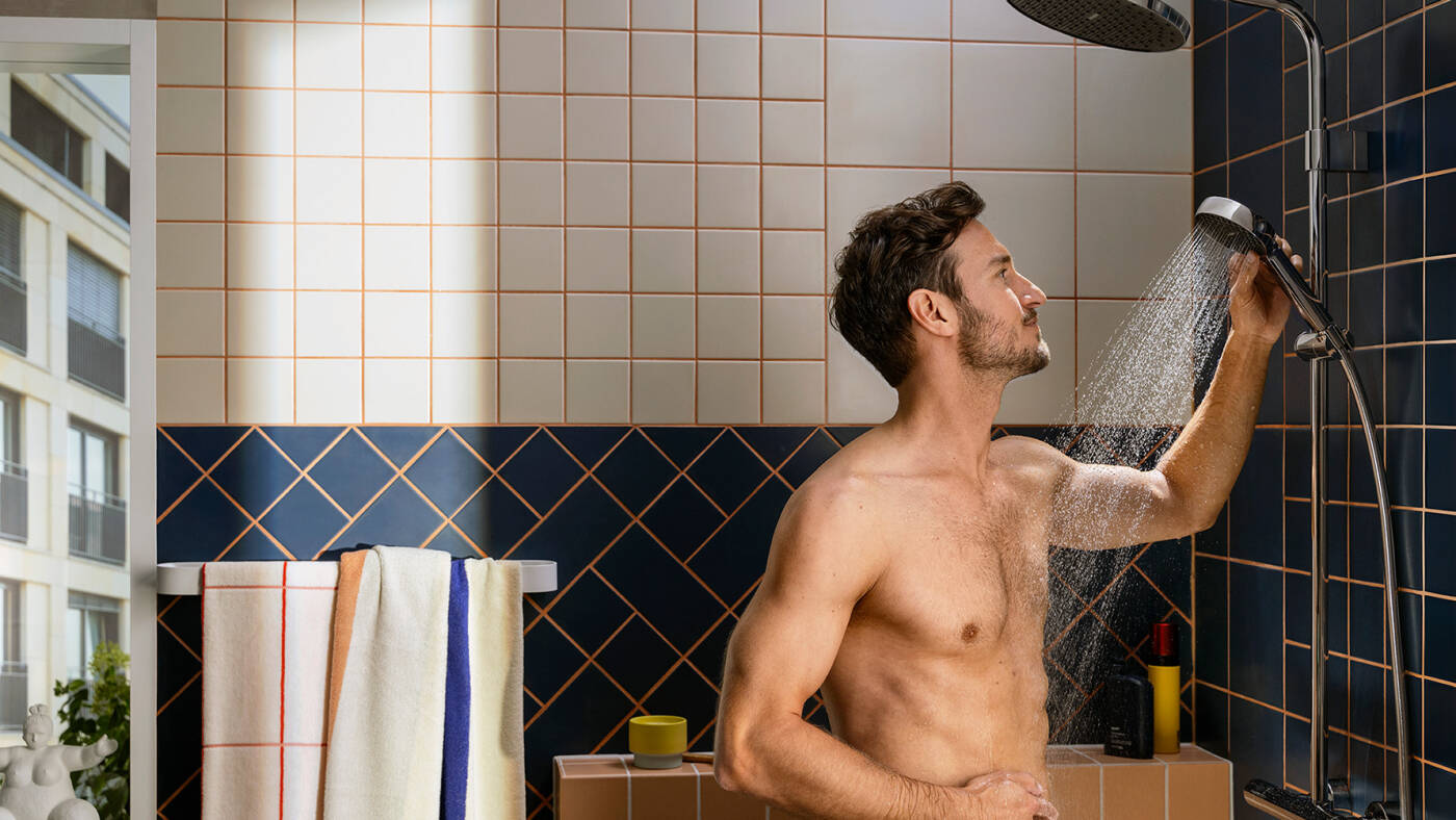 Man doucht met ronde, cilindrisch vormgegeven handdouche.