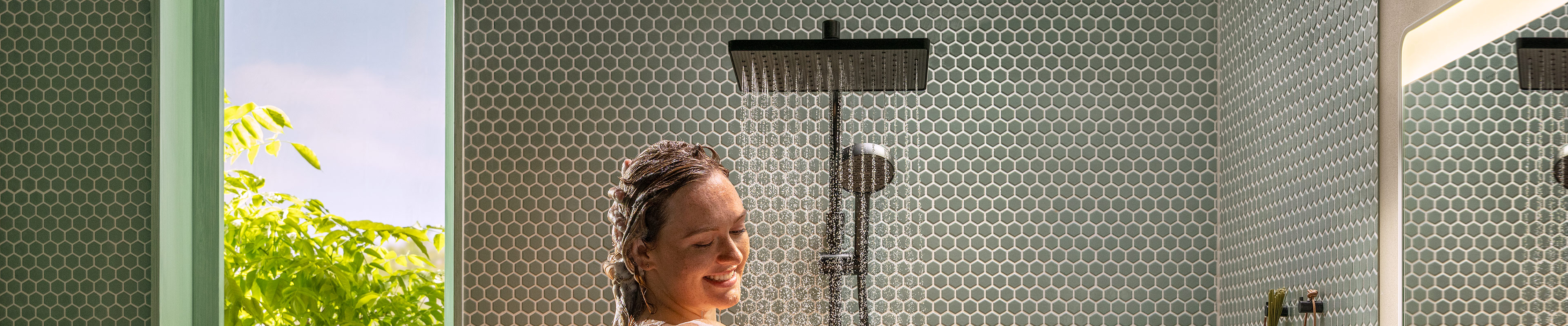 Radosna kobieta podczas kąpieli pod prysznicem z Activera Q Showerpipe.