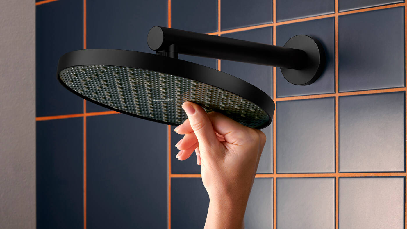 Woman’s hand rubbing limescale off Activera overhead shower.