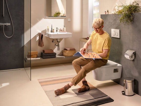 Man sitting fully clothed on the hansgrohe toilet.