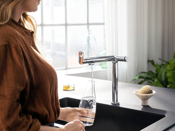 Femme tirant de l’eau d’un mitigeur de cuisine rectiligne.