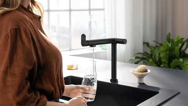 Frau zapft Trinkwasser aus der Küchenarmatur Aqittura M91.
