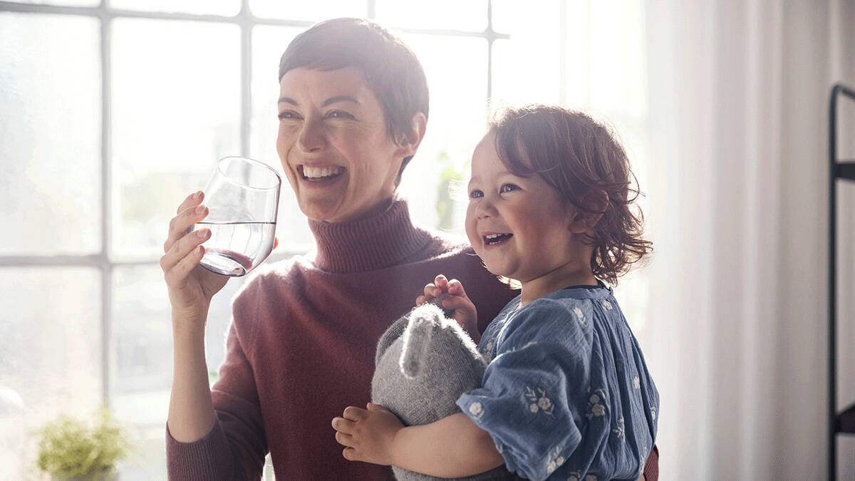 Mutter und Kind genießen lachend gefiltertes Trinkwasser.