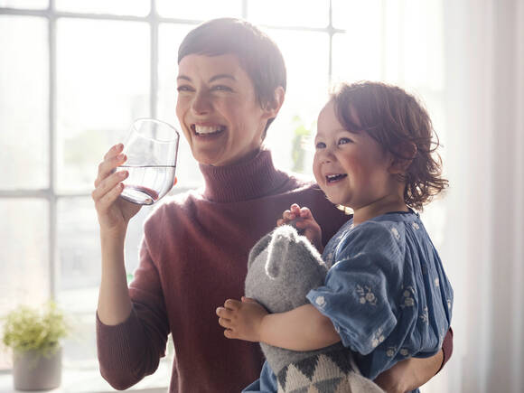 Majka i dijete s osmjehom uživaju u filtriranoj vodi za piće.