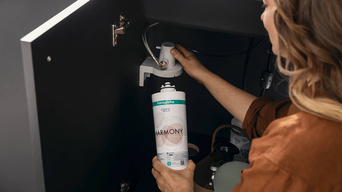 Frau schraubt neuen hansgrohe Filter in der Spüle an.
