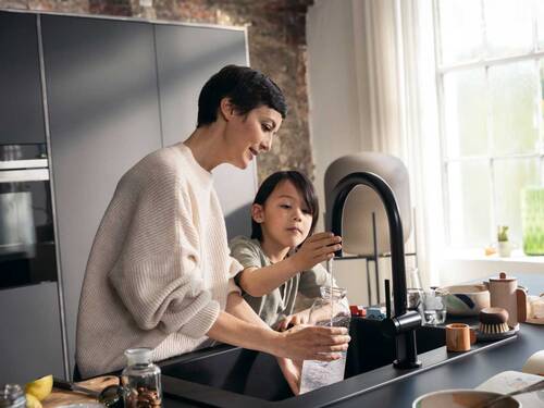 Woman fills bottle at hansgrohe faucet.