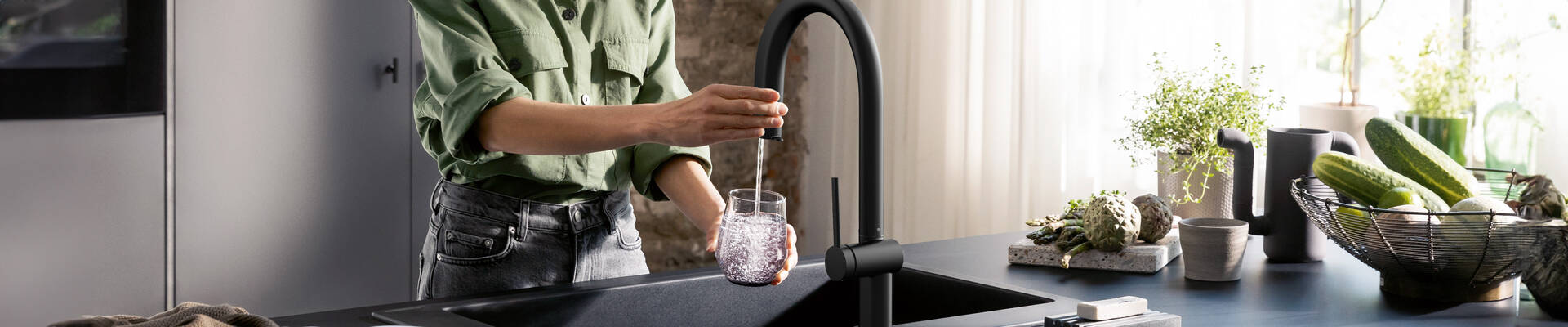 Frau befüllt ein Glas Wasser mit Aqittura M91