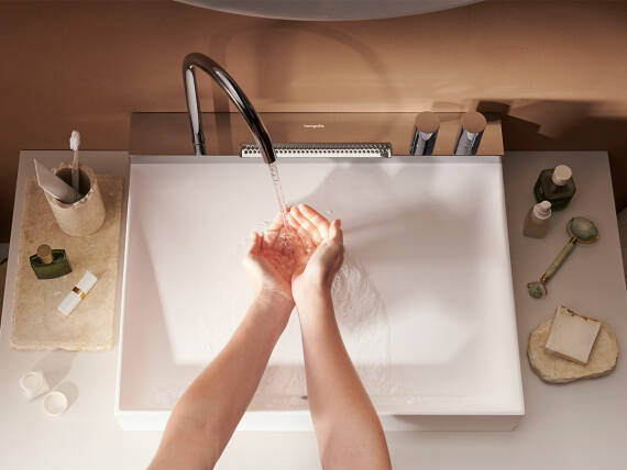 Kvinde vasker hænder ved håndvask med brusestråle.