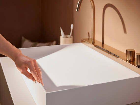 Kvindehånd strejfer hen over kanten på en hansgrohe håndvask.