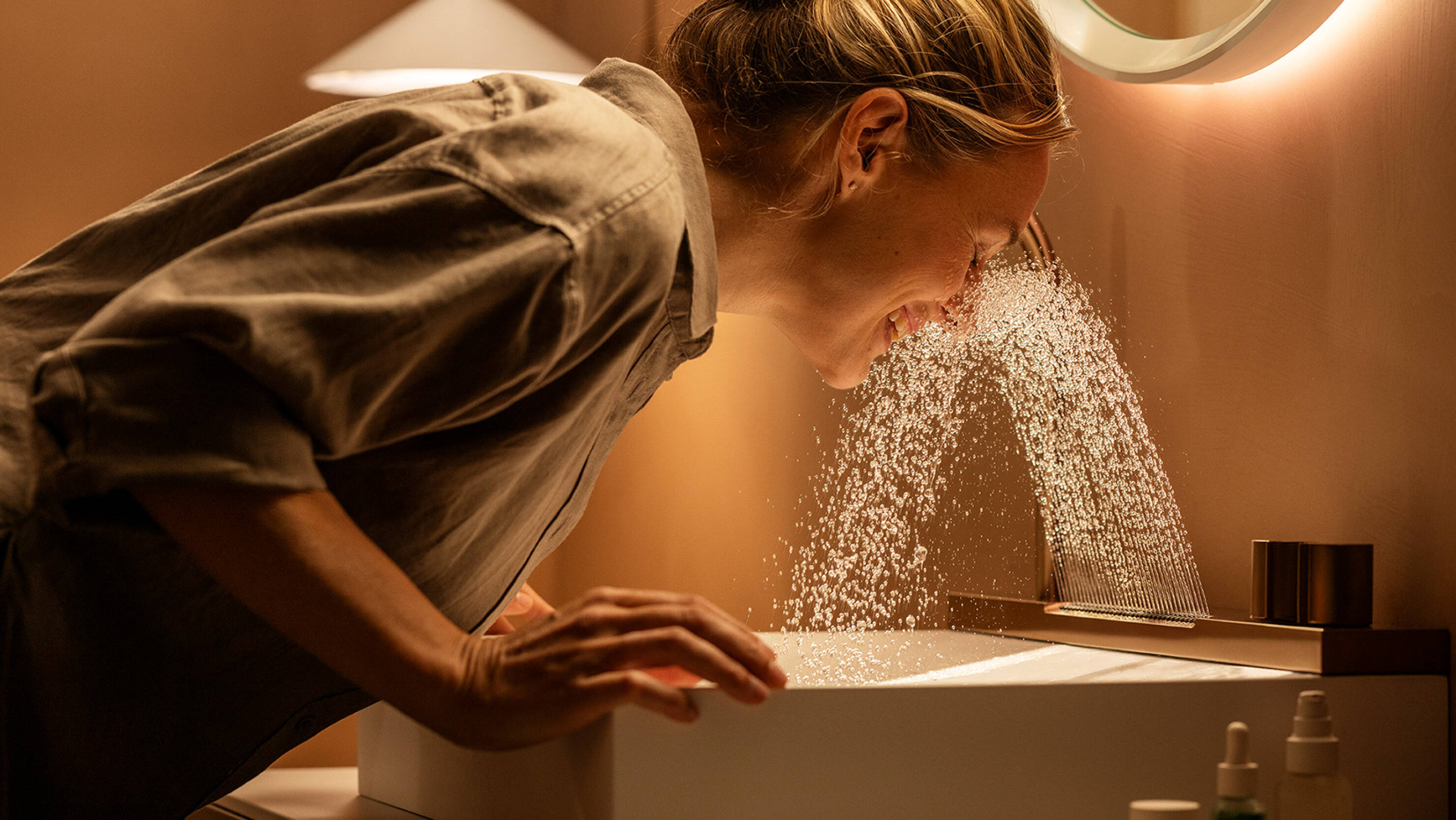 Una donna entusiasta si gode il nuovo getto Rain sul lavabo.