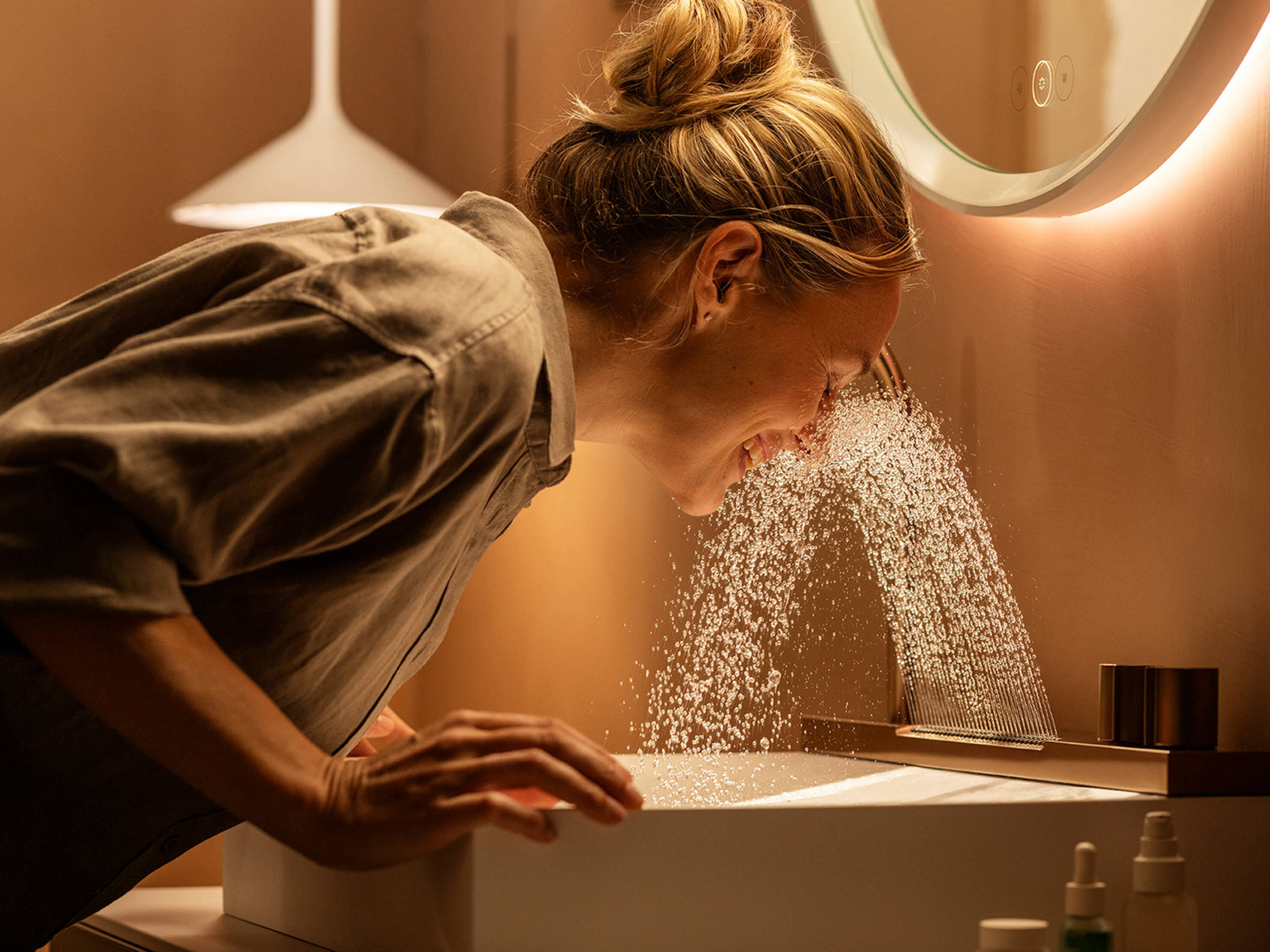 Femme enthousiaste profite du nouveau jet Rain sur le plan de lavabo.