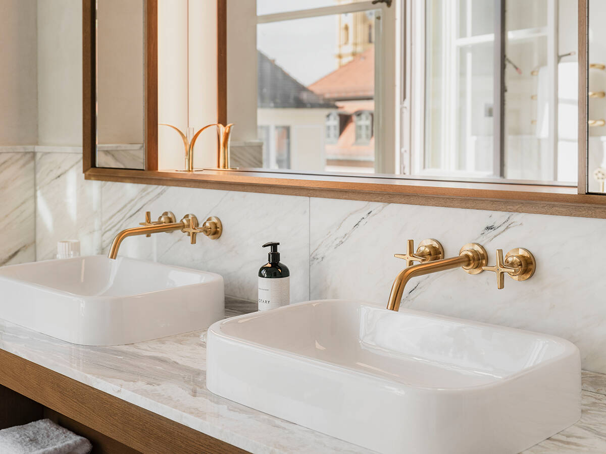 Two gold-colored AXOR faucets in a hotel bathroom.