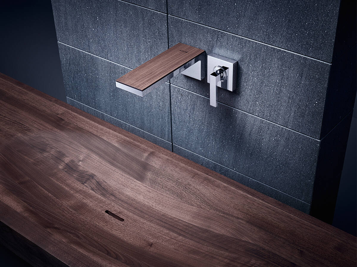 Wandarmatur mit Hebelgriff und Holzplatte auf dem Auslauf.