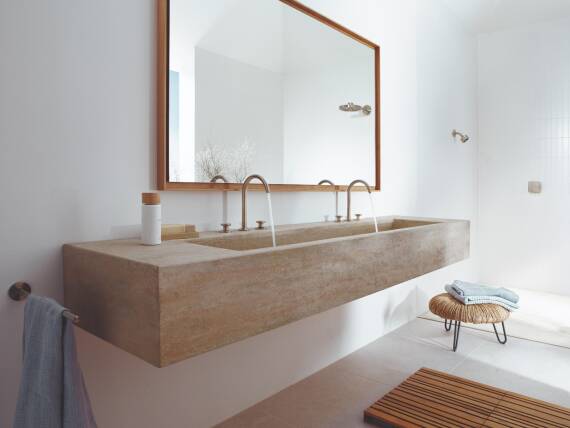 Умывальник из травертина со смесителями AXOR One.