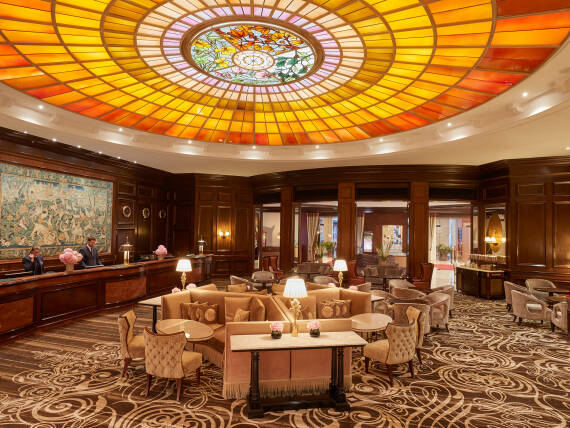Lobby of Hotel Vier Jahreszeiten Kempinski Munich featuring the historic stained-glass dome and elegant seating areas.