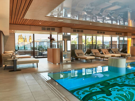 Relaxation area at the Vier Jahreszeiten Spa in Hotel Vier Jahreszeiten Kempinski Munich with loungers beside the pool.