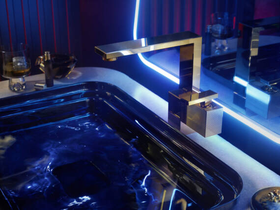 AXOR Edge washbasin faucet in Polished Gold Optic, installed in a modern bathroom with blue LED lighting. AXOR Edge washbasin faucet in Polished Gold Optic, installed in a modern bathroom with blue LED lighting.
