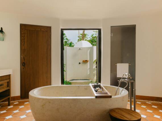 Luminoso baño con bañera de piedra independiente y mezclador AXOR Montreux, con vistas a una ducha exterior privada