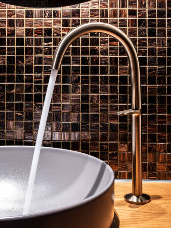 Detail shot of an AXOR One basin faucet in Brushed Bronze surface in action Detail shot of an AXOR One basin faucet in Brushed Bronze surface in action