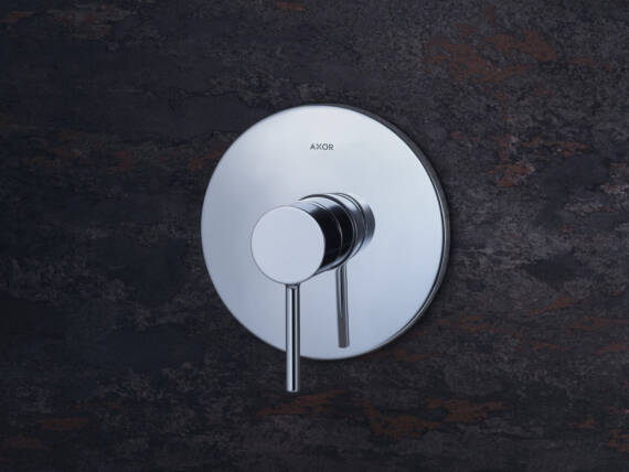 Close-up of the AXOR Starck single lever shower faucet for concealed installation with pin handle on a dark background. Close-up of the AXOR Starck single lever shower faucet for concealed installation with pin handle on a dark background.