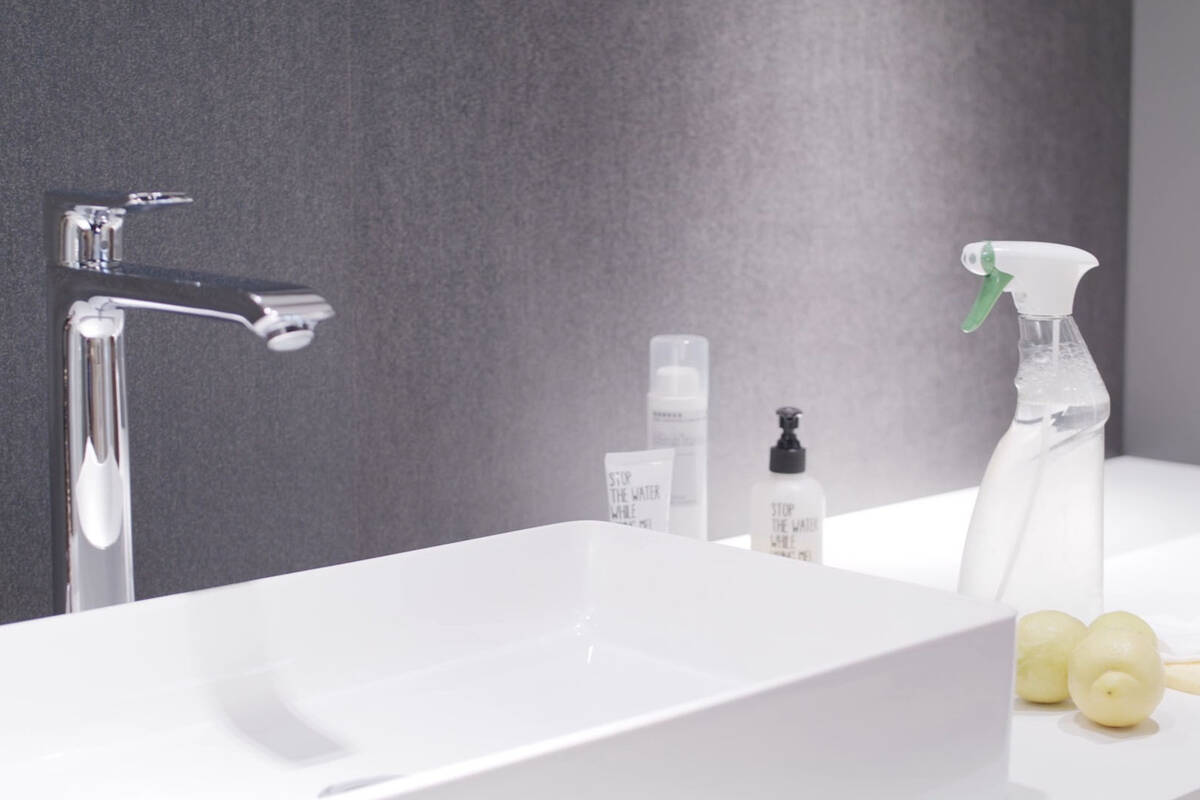 Reinigungsmittel stehen neben Waschbecken und Armatur