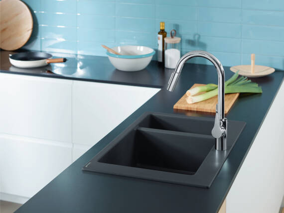 Woman operates a kitchen tap with the hansgrohe water-saving function.