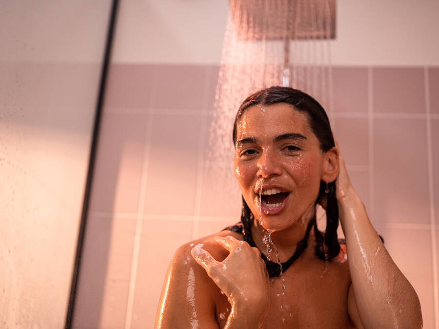Femme se douchant avec la douche de tête Crometta de hansgrohe.