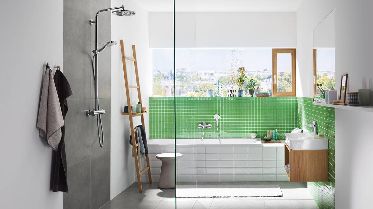 Bañera y cabina de ducha con azulejos y pared de cristal situada