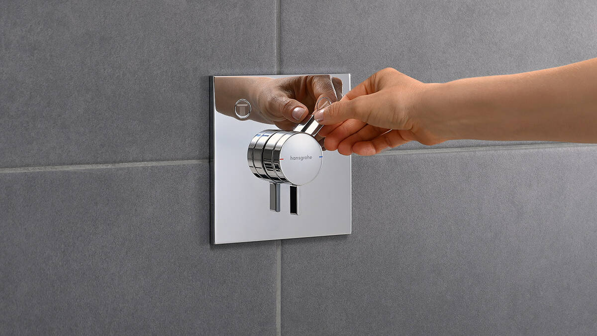 Man uses hansgrohe DuoTurn tap under the shower.