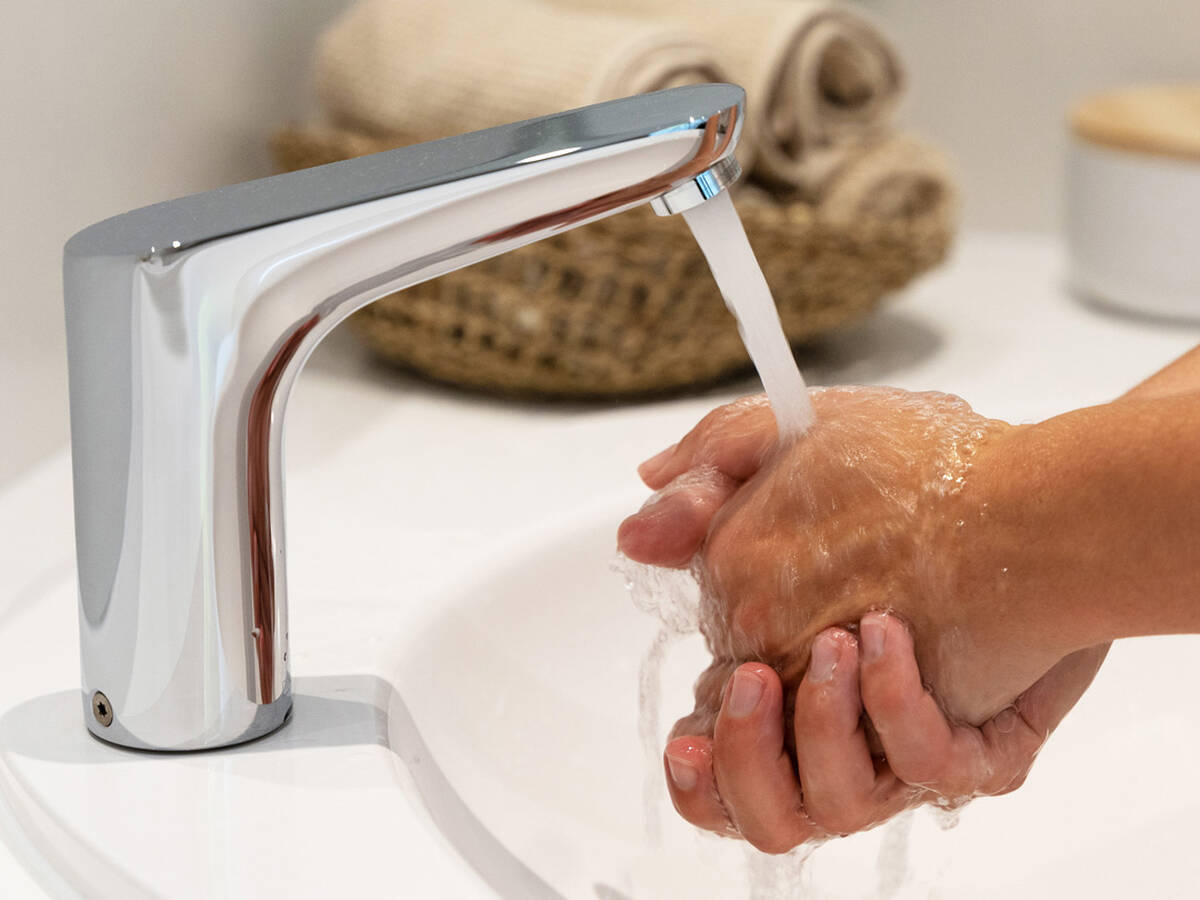 Waschende Hände unter hansgrohe Elektronikarmatur.