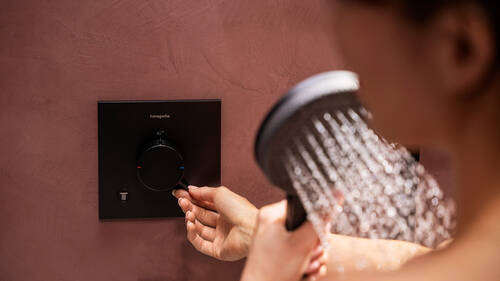 Ručne ovládaný plochý, čierny sprchový termostat značky hansgrohe.