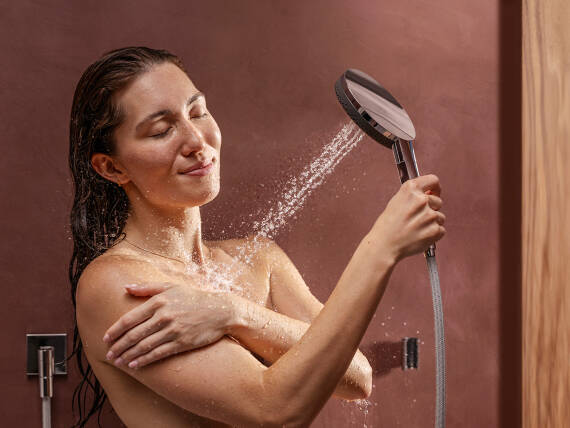 Una mujer duchándose con una teleducha de hansgrohe y sus accesorios.