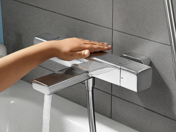 Egy kéz megérinti az Ecostat E kádtermosztátot.