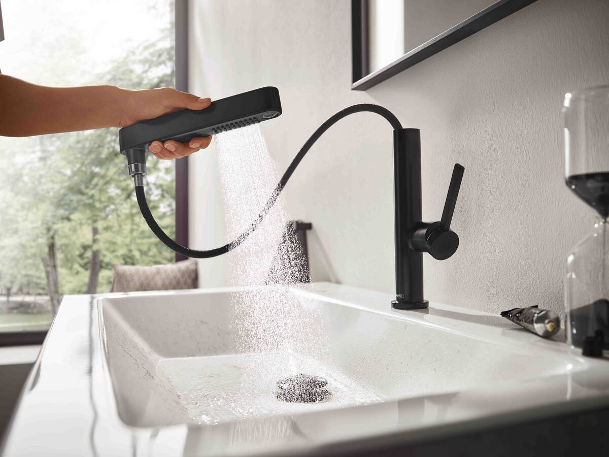 Main tenant la douchette à main hansgrohe Finoris déployée en noir mat.