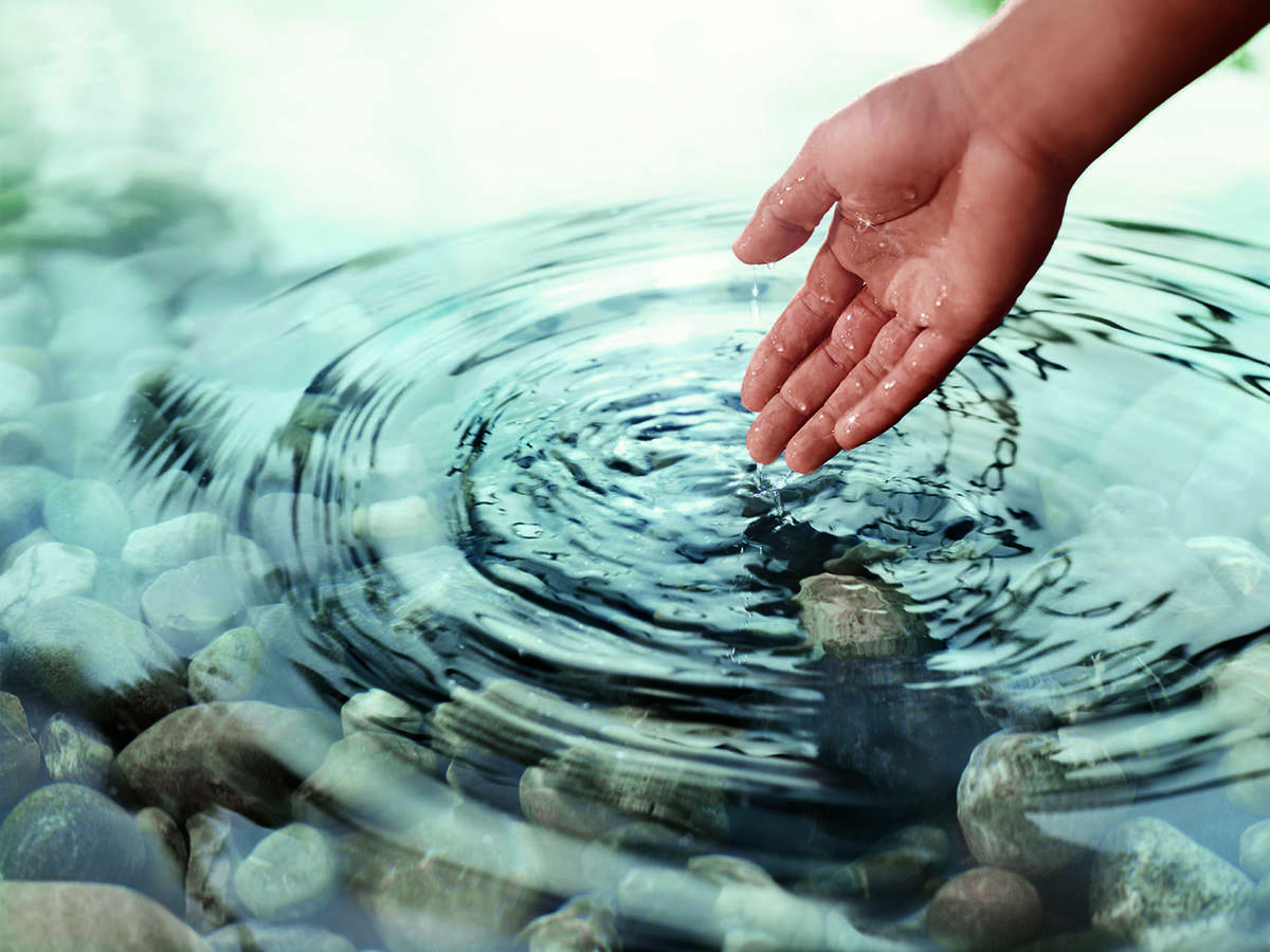Hand leaving ripples in water.