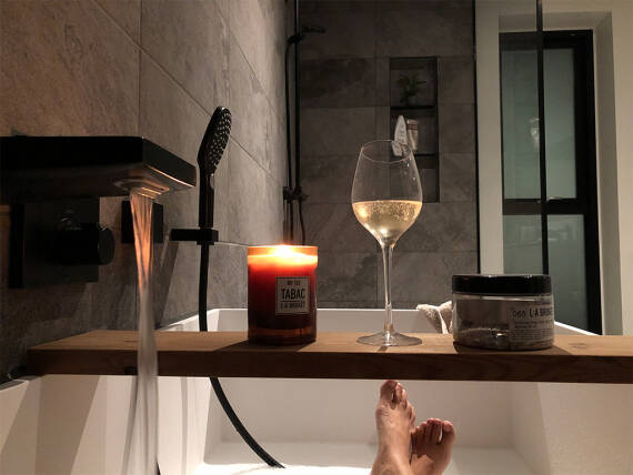 Salle de bains apaisante avec bougie, verre de vin et mitigeur moderne.