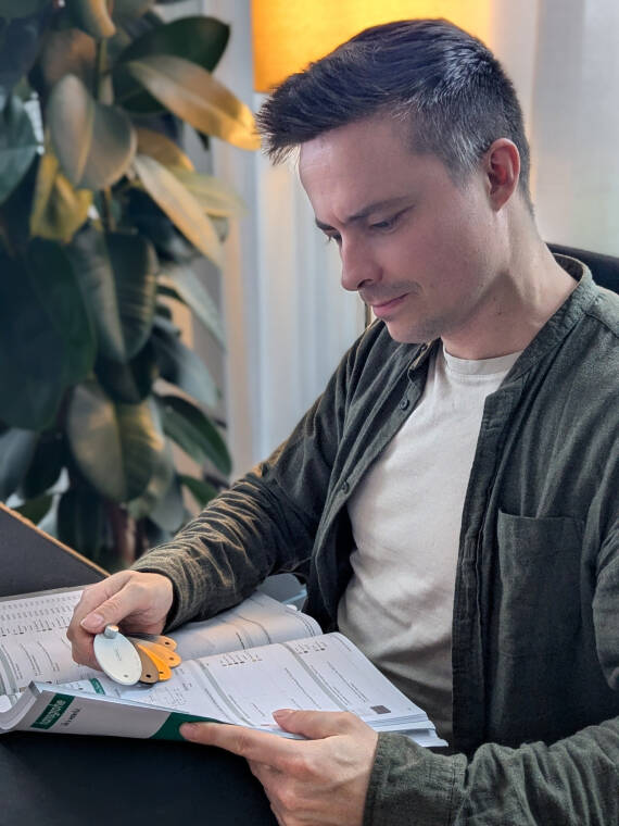 Personne plongée dans la lecture de documents à un bureau, lumière chaude en arrière-plan.