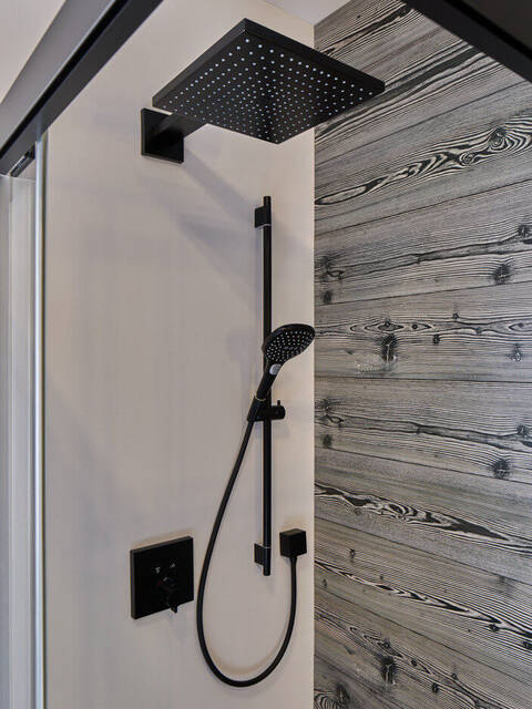 Schwarze Kopf- und Handbrause, weiß-schwarze Holzwand	