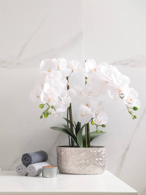 Waschtisch mit marmorierter Rückwand und blühender Orchidee