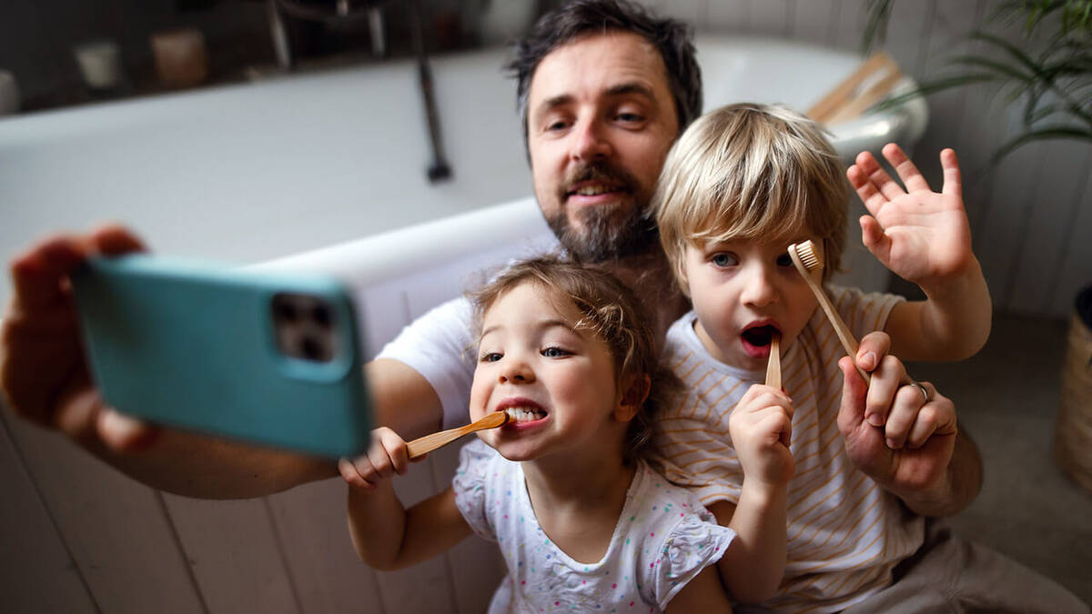 Vater mit Kindern beim Zähneputzen im Bad