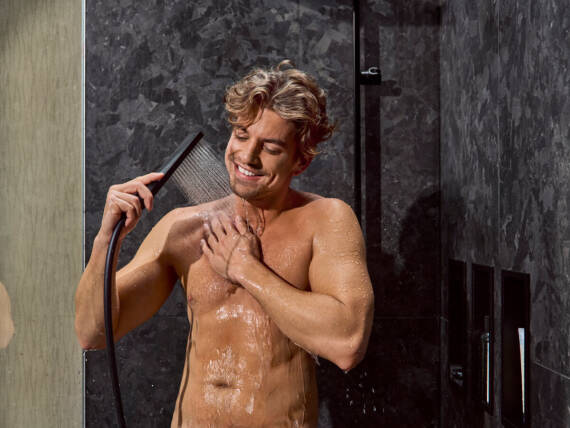 Een man doucht met een Economy douche van hansgrohe.