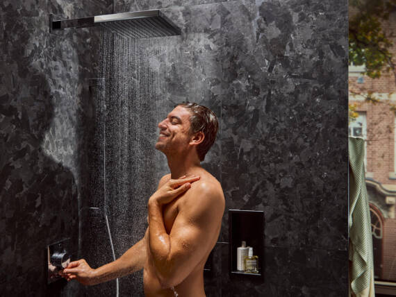 Man staat onder een open waterbesparende douche.