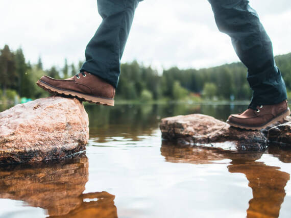 En person krydser vand på sten.