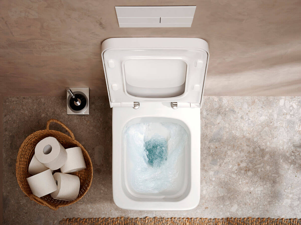 Bad mit wandhängender Toilette und getätigter Wasserspülung.