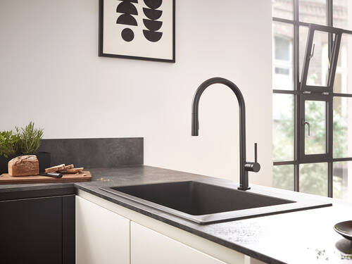Woman cleaning strawberries on kitchen faucet.