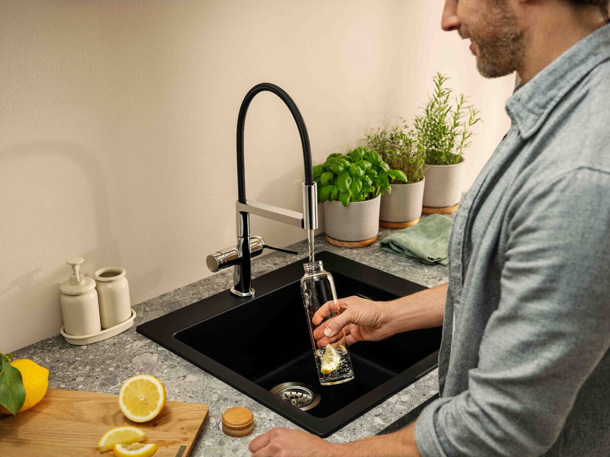 Mand fylder drikkeflaske med hansgrohe køkkenarmatur.
