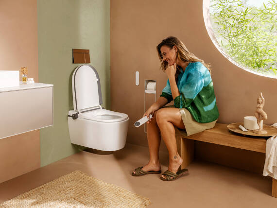 Frau bedient hansgrohe LavaPura Element Dusch-WC in ihrem Badezimmer.