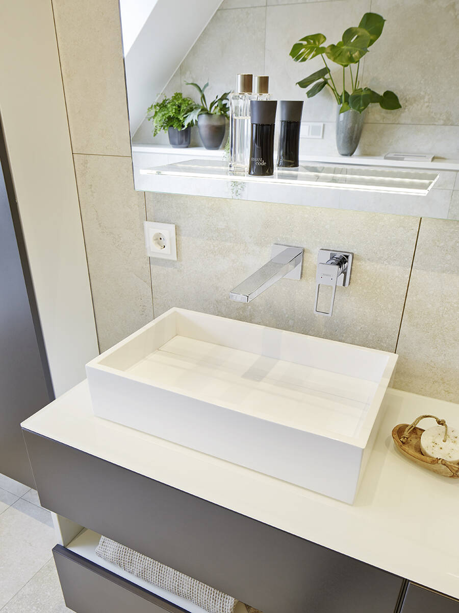 Wandhängende Chromarmaturen im hellen Bad.